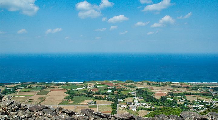 Veduta dell'Isola di Kume con campi coltivati e mare all'orizzonte.