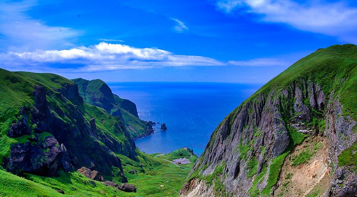 Paesaggio costiero dell'isola Rebun con colline verdi e mare.