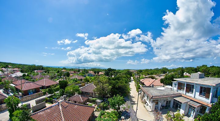 Vista panoramica dell'isola Taketomi con case tradizionali e cielo sereno.