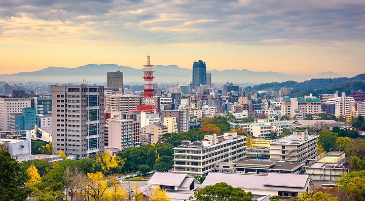 Vista panoramica della città di Kumamoto con edifici moderni e colline in lontananza.