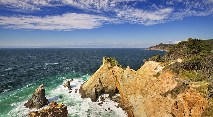 Costa rocciosa della penisola di Izu con mare blu e cielo sereno.