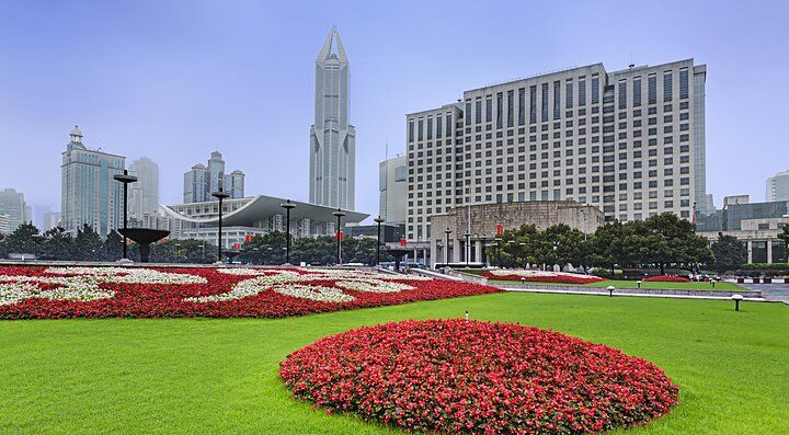 Piazza del Popolo a Shanghai con giardino fiorito e grattacieli sullo sfondo.