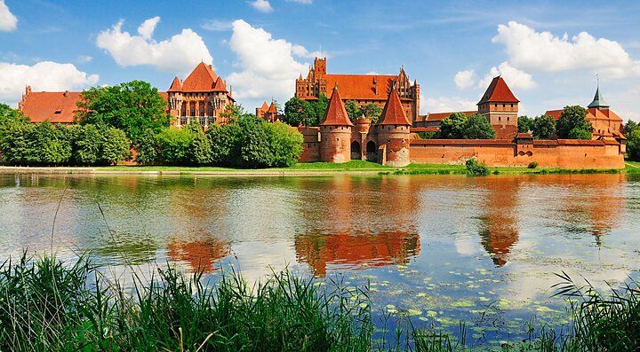 Castello medievale di mattoni rossi in Polonia riflesso nell'acqua.