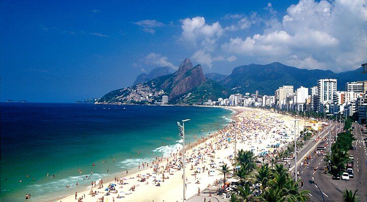 Spiaggia affollata a Rio de Janeiro, Brasile, con montagne sullo sfondo.