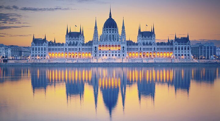 Il Parlamento di Budapest illuminato al tramonto riflesso nel Danubio
