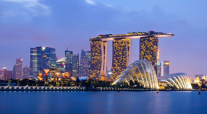 Skyline di Singapore al tramonto con Marina Bay Sands illuminato.