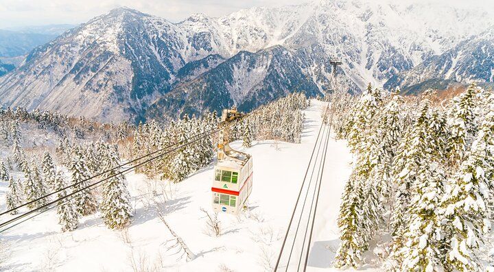 Funivia Shinhotaka tra montagne innevate e foresta.