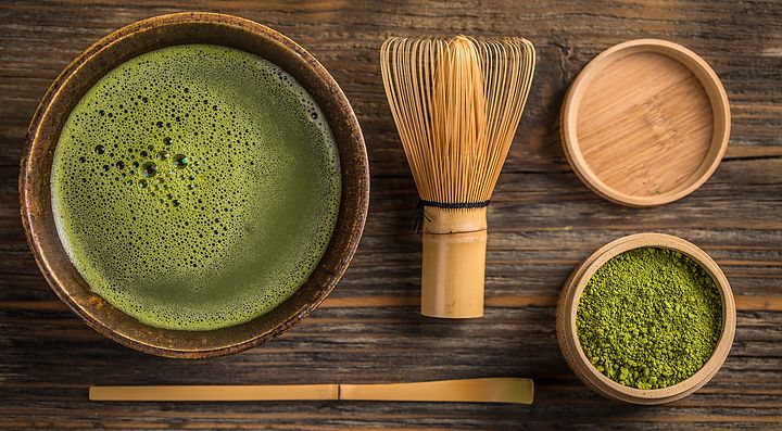 Tè matcha giapponese con accessori tradizionali su tavola di legno.
