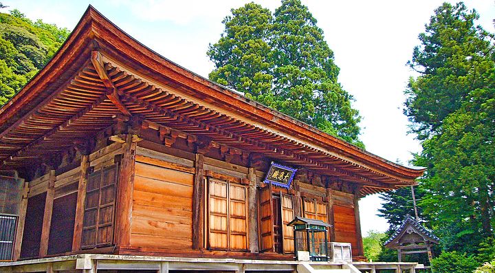 Tempio Onsenji in legno circondato da alberi verdi.