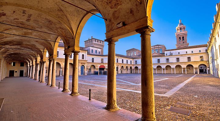 Piazza medievale di Mantova con loggia e torre sullo sfondo.