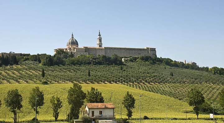 Paesaggio delle colline delle Marche con edificio storico sullo sfondo.