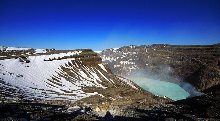 Il cratere del vulcano Aso con un lago turchese.