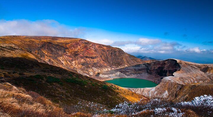 Il cratere vulcanico del Monte Zao con un lago verde al centro.