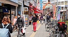 Strada affollata con negozi e bici nel quartiere di Koenji, Tokyo.