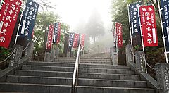 Scala con bandiere colorate sul monte Mitake avvolta nella nebbia.
