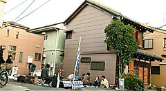 Strada di Yanaka con persone sedute e piccole case tradizionali giapponesi.