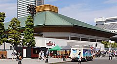 Il Ryogoku Kokugikan a Tokyo con visitatori e camion nel parcheggio.