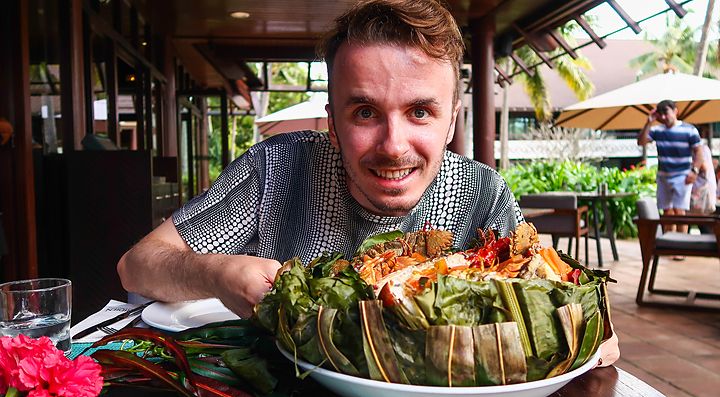 Una persona al ristorante con un piatto di bougna, specialità della Nuova Caledonia.