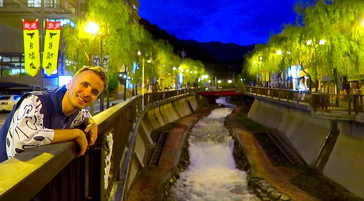 Marco Togni su un ponte a Gero Onsen illuminato di sera.