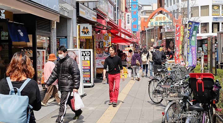 Strada affollata con negozi e bici nel quartiere di Koenji, Tokyo.