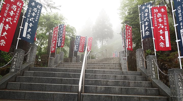Scala con bandiere colorate sul monte Mitake avvolta nella nebbia.