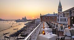 Tavoli pronti per la cena all'hotel Danieli Venezia, e in lontananza il sole al tramonto.