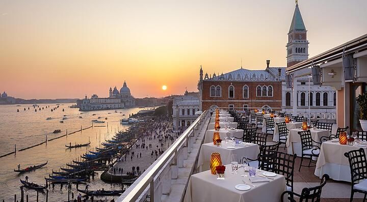Tavoli pronti per la cena all'hotel Danieli Venezia, e in lontananza il sole al tramonto.