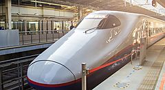 Treno shinkansen fermo in stazione, al tramonto.