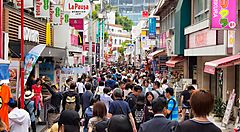 Strada affollata a Harajuku con negozi colorati e passanti.