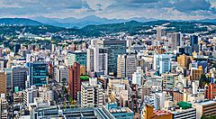 Veduta panoramica della città di Sendai con edifici moderni e colline sullo sfondo.