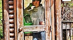 Marco Togni in cabina telefonica di legno usa un telefono pubblico verde.