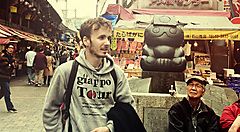 Marco Togni a Ueno, Tokyo, in un mercato affollato con una statua sullo sfondo.