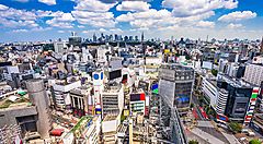 Skyline urbano di Shibuya, Tokyo, con edifici moderni e cielo azzurro.
