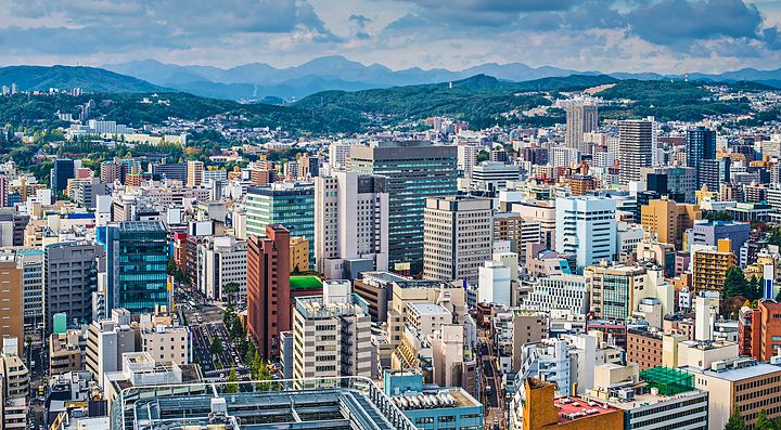 Veduta panoramica della città di Sendai con edifici moderni e colline sullo sfondo.