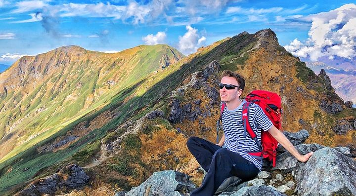 Escursionista seduto sulle montagne in Giappone sotto un cielo sereno.