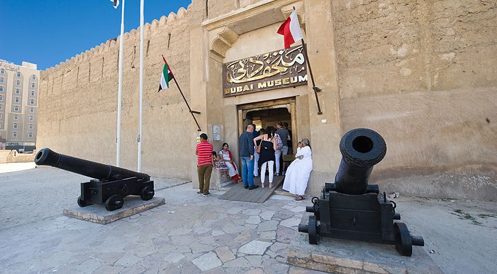 Entrata del Museo di Dubai con cannoni storici e visitatori.