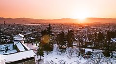 Tramonto su Aizu innevata con vista su edifici e montagne.