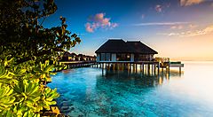 Bungalow su palafitte alle Maldive al tramonto.