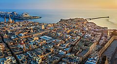 Veduta aerea di una città costiera a Malta al tramonto.