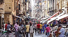 Strada affollata nel centro di Napoli con bancarelle e passanti.