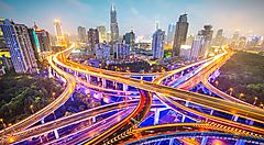 Strade sopraelevate illuminate nello skyline notturno di Shanghai.