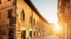 Strada storica di Verona al tramonto con edifici antichi.