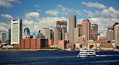 Skyline di Boston vista dall'acqua con un traghetto in primo piano.