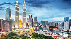 Skyline di Kuala Lumpur con le Torri Petronas illuminate al tramonto.