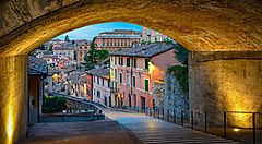 Strada pittoresca con case colorate vista da un arco a Perugia.
