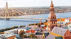 Vista panoramica del centro storico di Riga con il fiume Daugava e un ponte sullo sfondo.