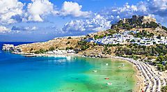 Spiaggia e mare cristallino a Rodi con vista del villaggio e dell'acropoli.
