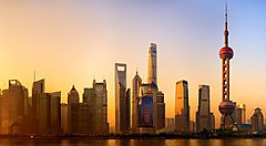 Skyline di Shanghai al tramonto con grattacieli illuminati.