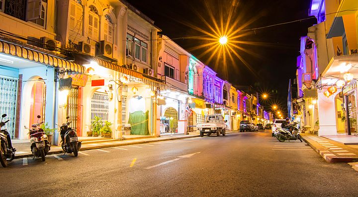 Strada illuminata nel centro storico di Phuket con edifici colorati di notte.