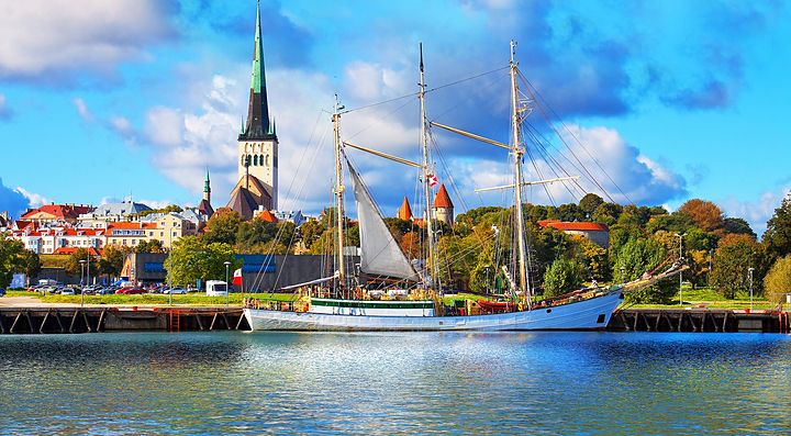 Veliero ormeggiato di fronte alla città di Tallinn con chiese e edifici sullo sfondo.